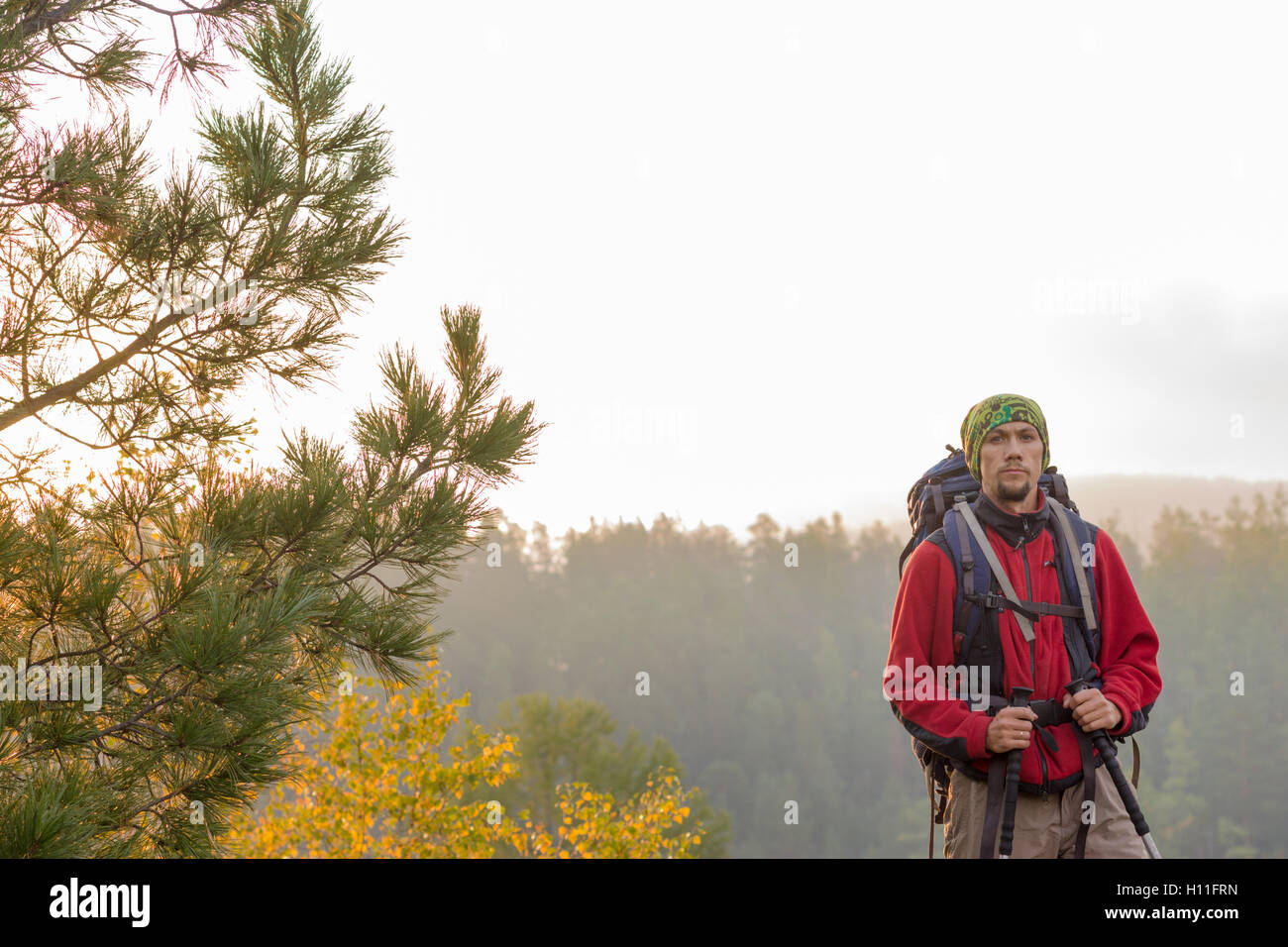 Uomo con zaino e trekking pole in bandana in piedi su una roccia all'alba  su uno sfondo autunno foresta Foto stock - Alamy