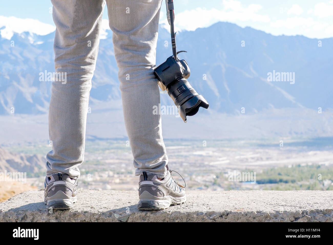 Fotografo di viaggio azienda reflex fotocamera professionale in scena della montagna. Foto Stock