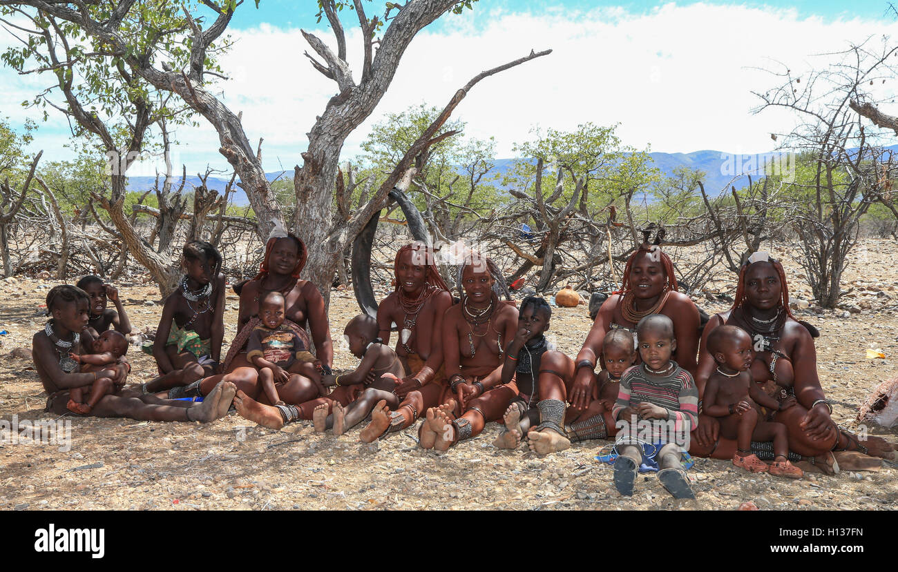 Gruppo di Himba donne e bambini seduti nel loro villaggio nella regione di Kunene di Namibia Foto Stock