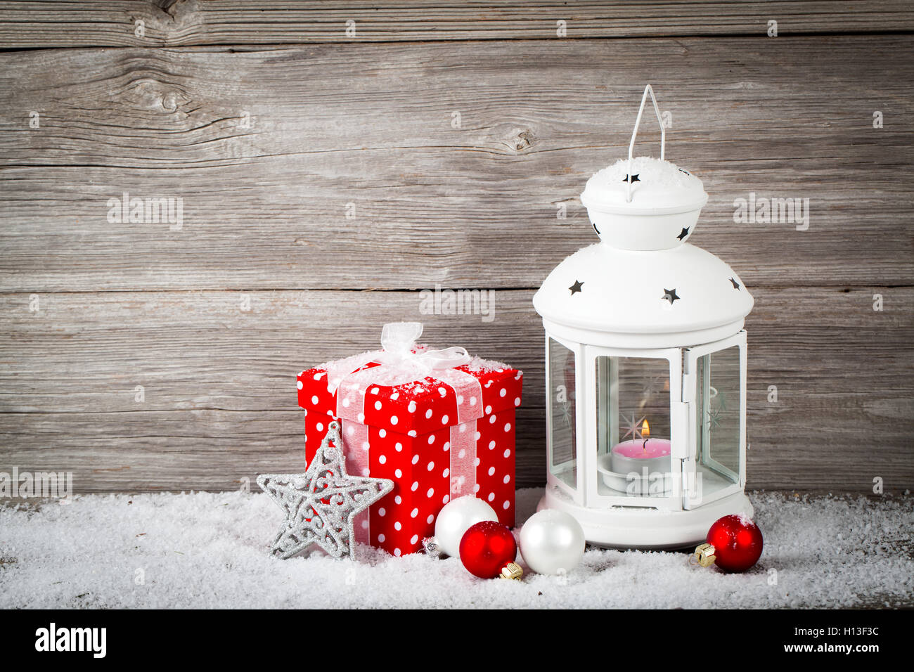 Lanterna di masterizzazione nella neve con decorazione di Natale, su legno b Foto Stock