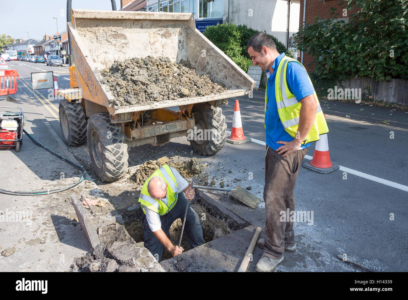 I lavoratori stradali foro di scavo su strada, St.Jude's Road, Englefield Green, Surrey, England, Regno Unito Foto Stock