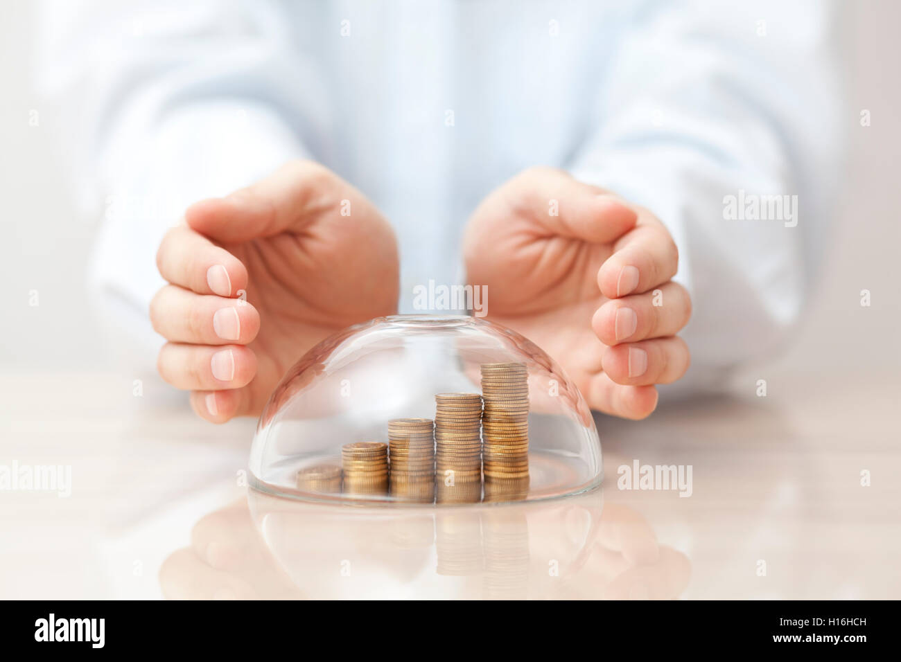 In aumento le monete protetti sotto una cupola di vetro e le mani Foto Stock