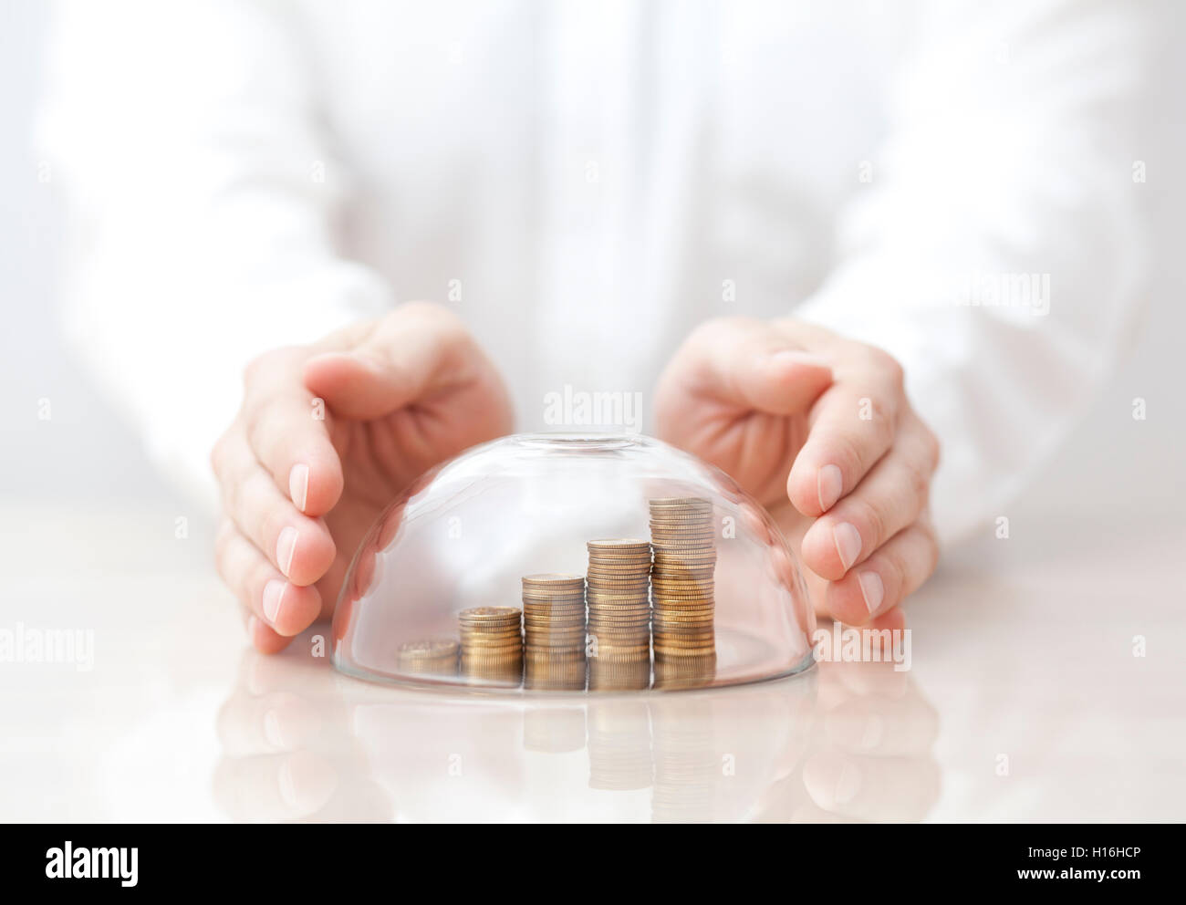 In aumento le monete protetti sotto una cupola di vetro e le mani Foto Stock