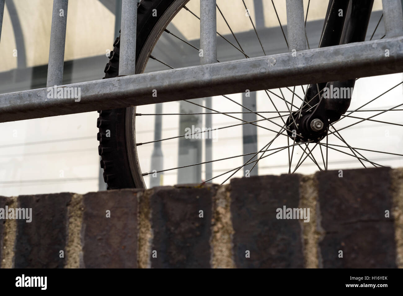 Parcheggiato commuter bike con una ringhiera. A ciclo singolo pneumatico e le razze sono visibili attraverso le ringhiere Foto Stock