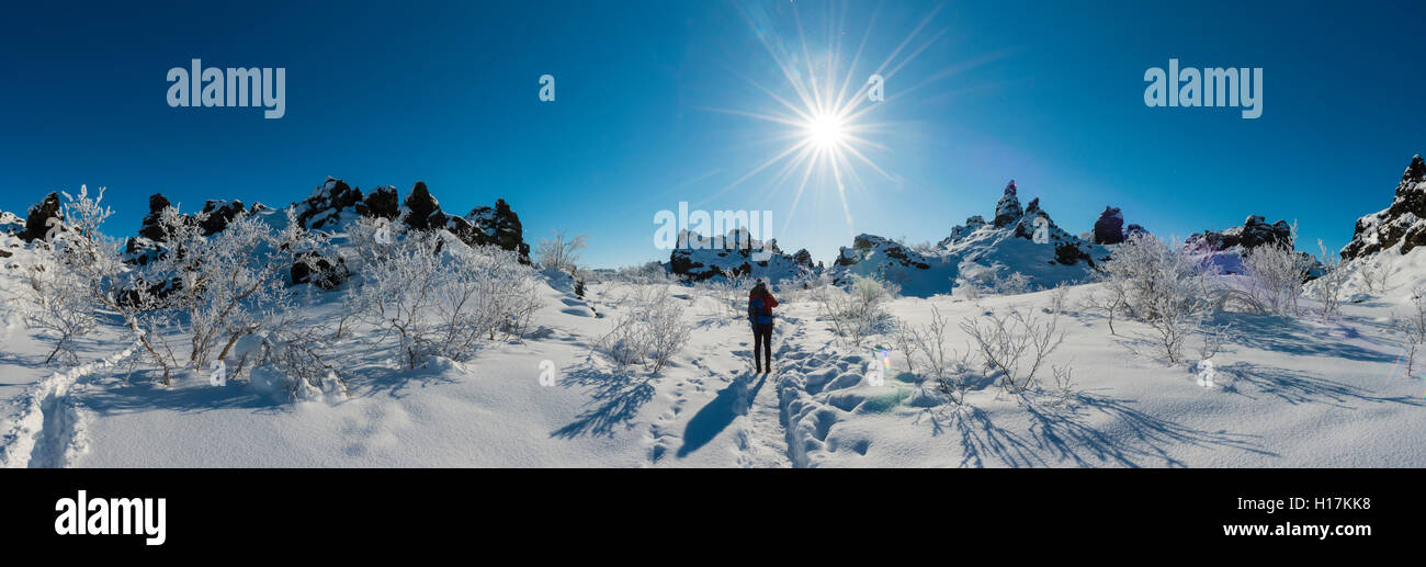 Donna sul sentiero nel paesaggio innevato, sole, campo di lava coperto di neve, Krafla sistema vulcanico, Dimmuborgir Parco Nazionale Foto Stock