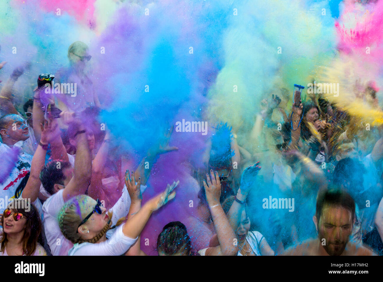 Migliaia di giovani donne e uomini stanno gettando il colore in polvere in aria presso il colorato Holi festival, Dresda, Sassonia, Germania Foto Stock