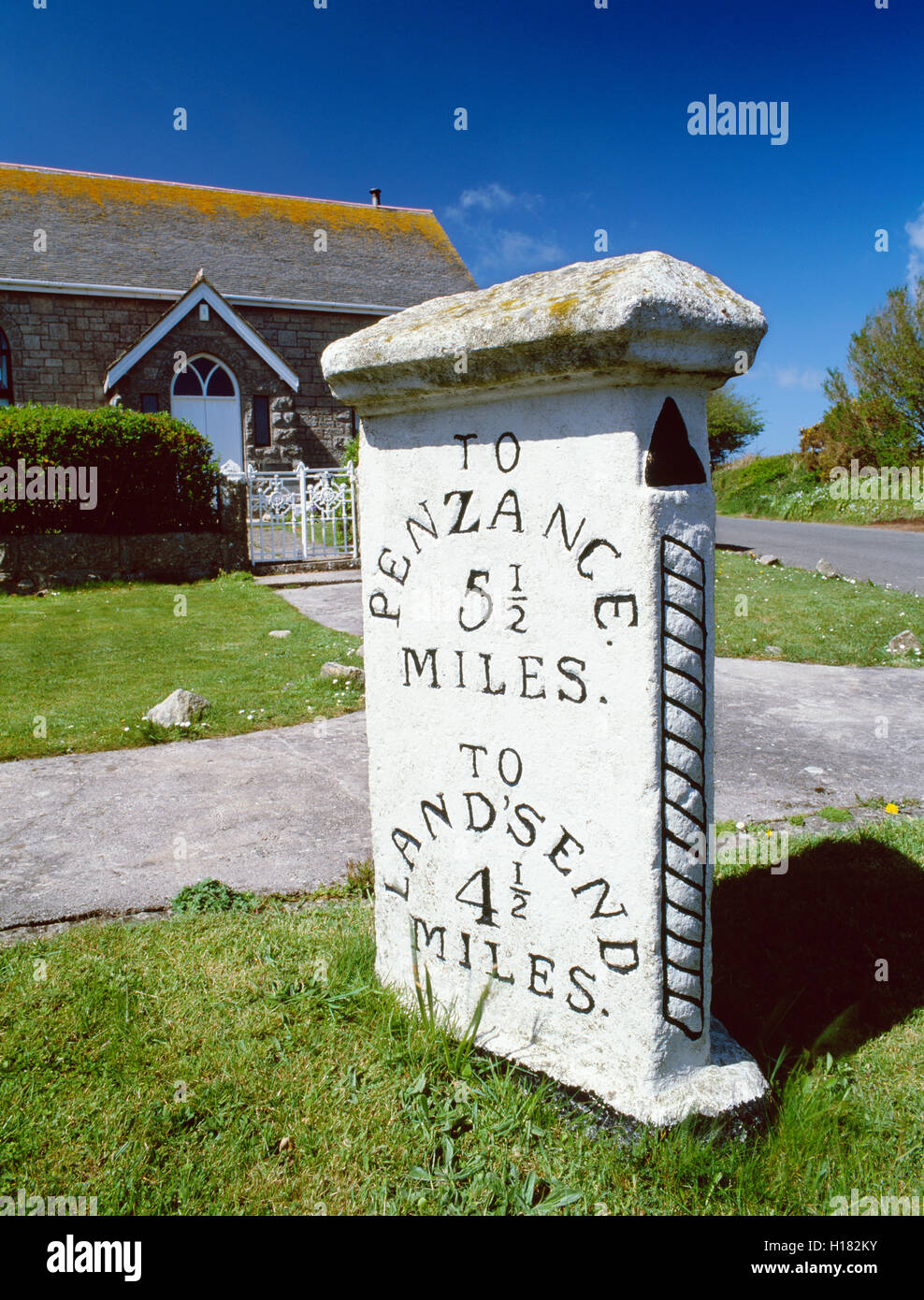 A tre facciate pietra miliare accanto a un convertito cappella sulla A30 strada tra Penzance e Land's End, Cornwall, South West England, Regno Unito Foto Stock
