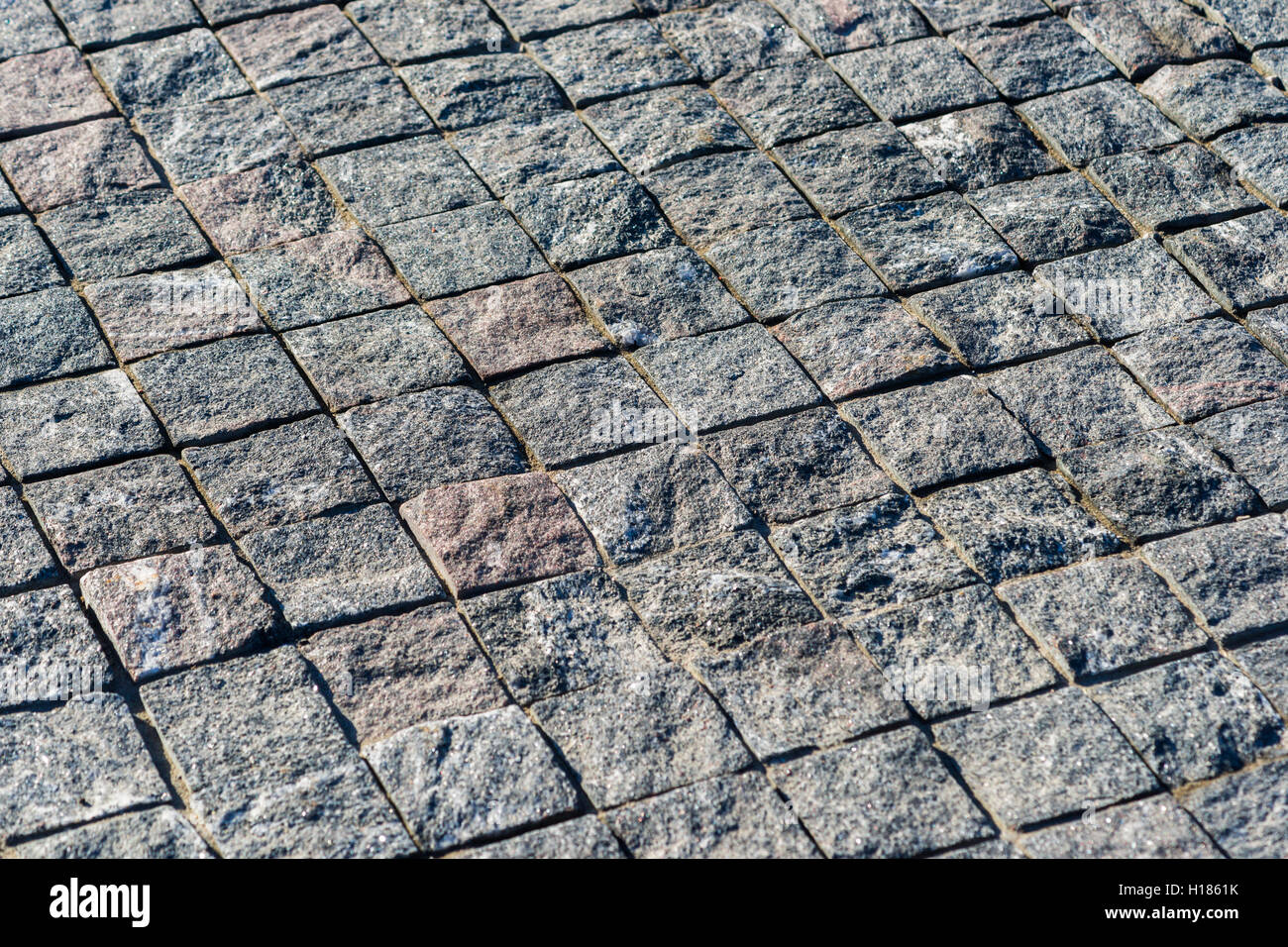 Superficie pavimentata con quadrato dei blocchi di granito. Pattern che deve essere utilizzato come una texture o dello sfondo. Foto Stock