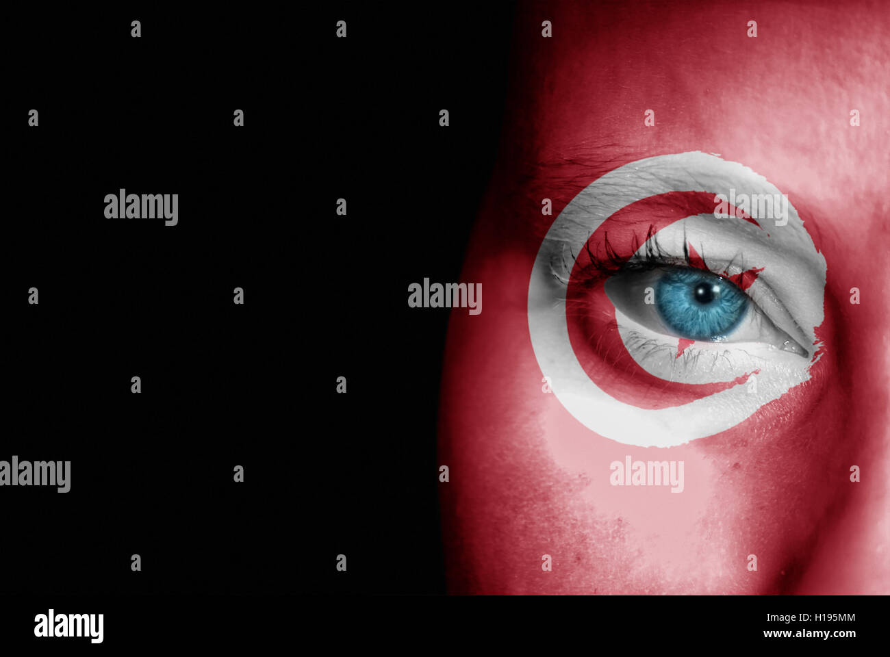 Una giovane donna con la bandiera della Tunisia dipinta sulla sua faccia sul suo modo ad un evento sportivo per mostrare il suo supporto. Foto Stock