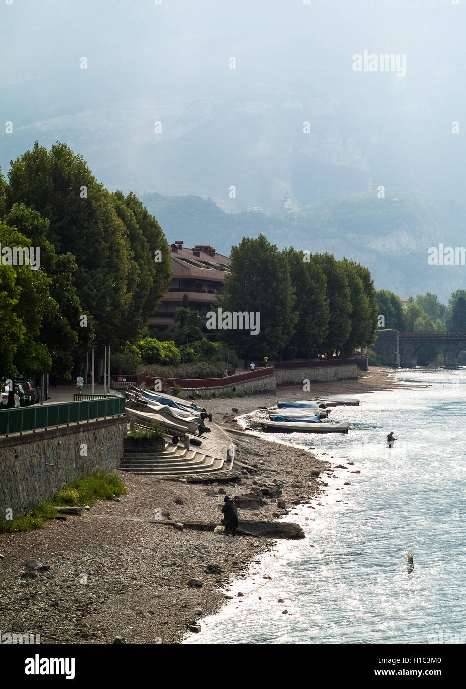 Due uomini la pesca nel fiume Adda su un oscuro mattina a Lecco, Italia Foto Stock