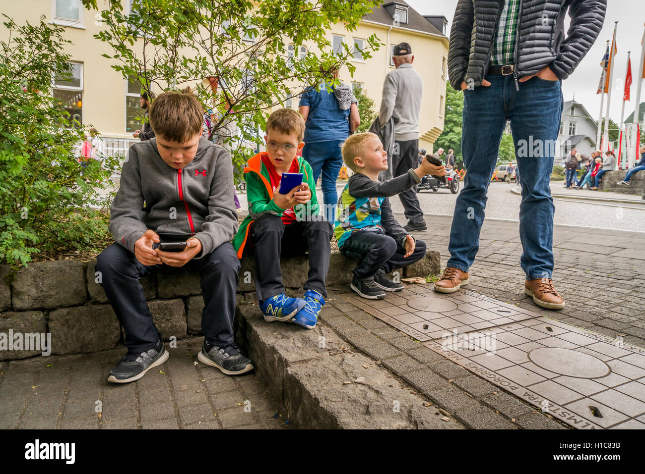 Ragazzi guardando gli smartphone all'aperto durante il Festival Menningarnott-Cultural a Reykjavik, Islanda Foto Stock