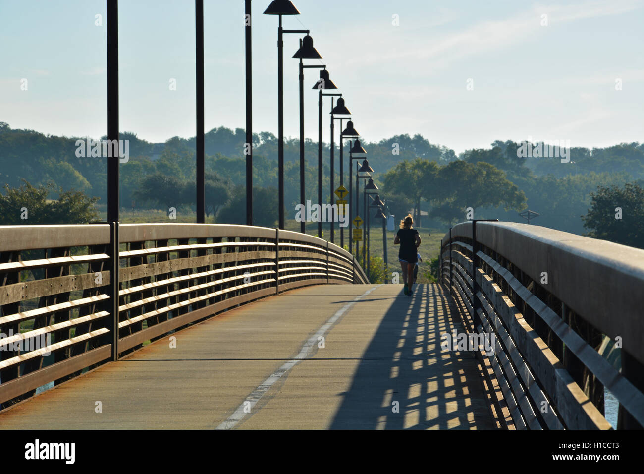 Un runner attraversa il Mockingbird punto passerella all'alba sul lato nord di White Rock Lake a Dallas. Foto Stock