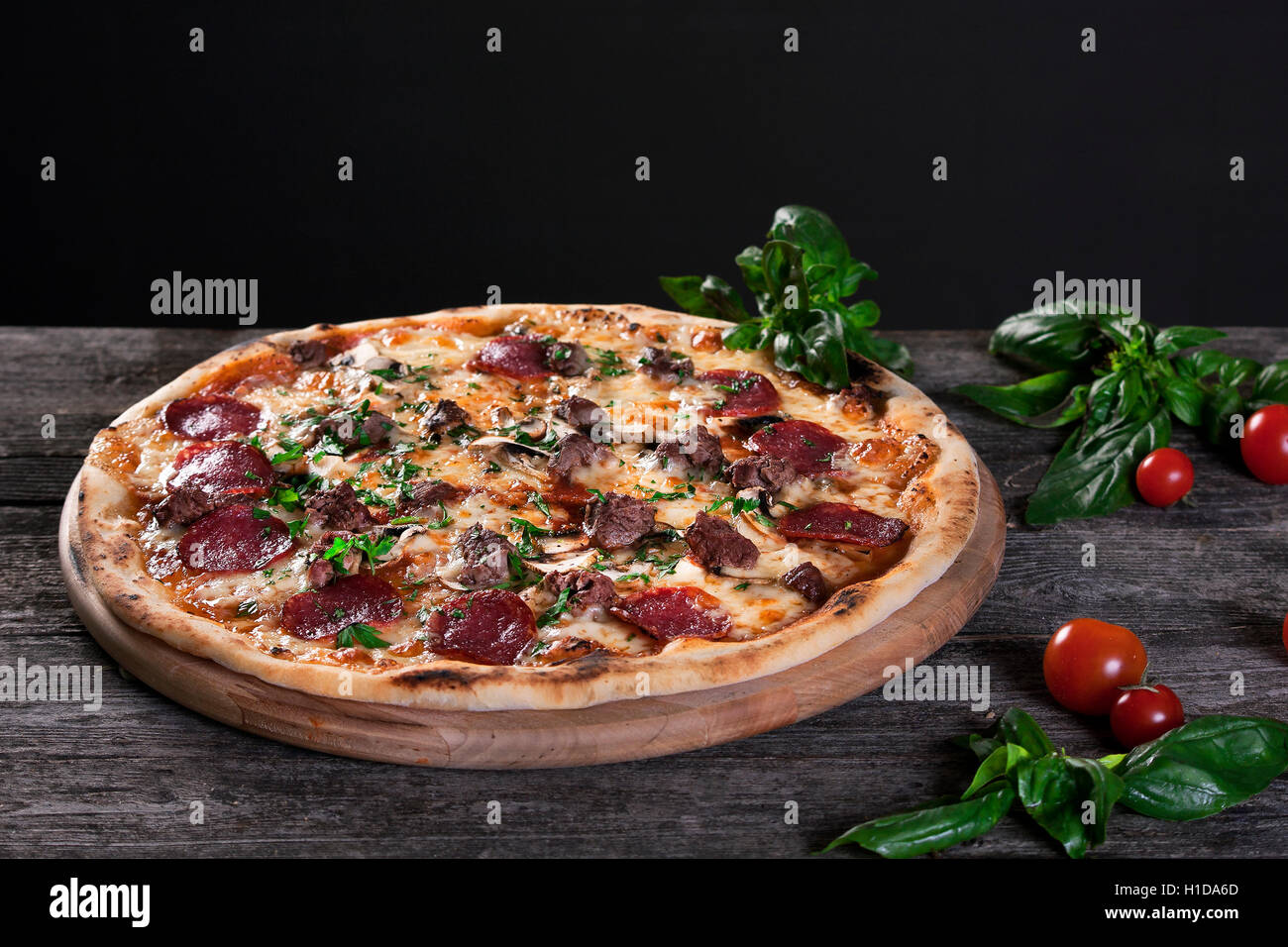 Salsiccia per Pizza Pizza con salumi, funghi, carni, carni bovine, formaggio e cipolle verdi su sfondo di legno. Vista dall'alto. Foto Stock