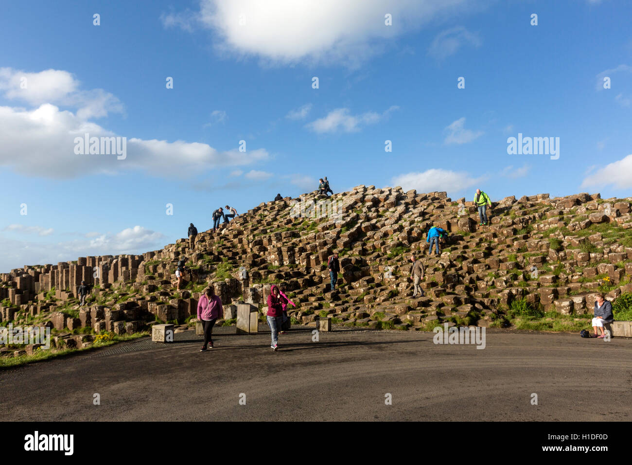 Tourist in piedi su colonne di basalto nel Giant's Causeway, Bushmills, County Antrim, Irlanda del Nord, Regno Unito Foto Stock