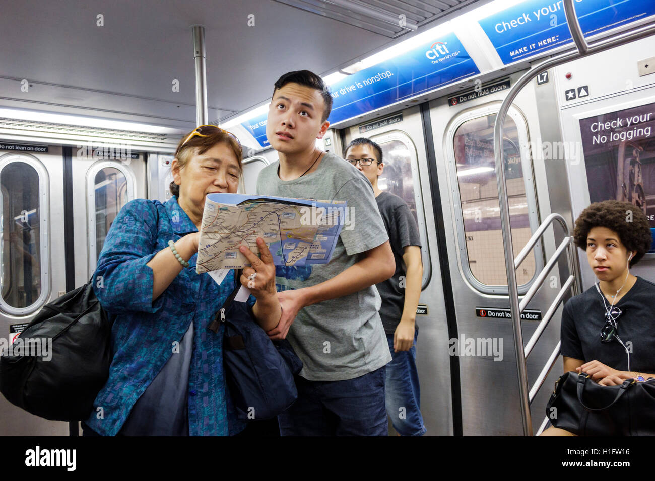 New York City,NY NYC Manhattan,metropolitana,MTA,treno,passeggeri passeggeri motociclisti,adulti asiatici,uomini maschi,donne femmine,in piedi,lettura Foto Stock