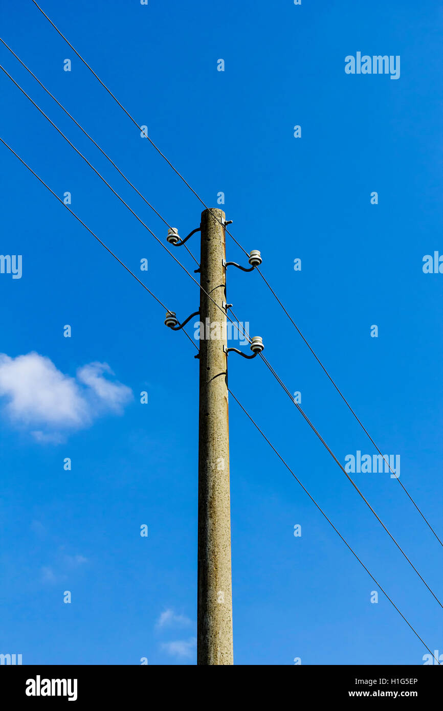 Vecchio cemento power-line isolato sul cielo blu Foto Stock