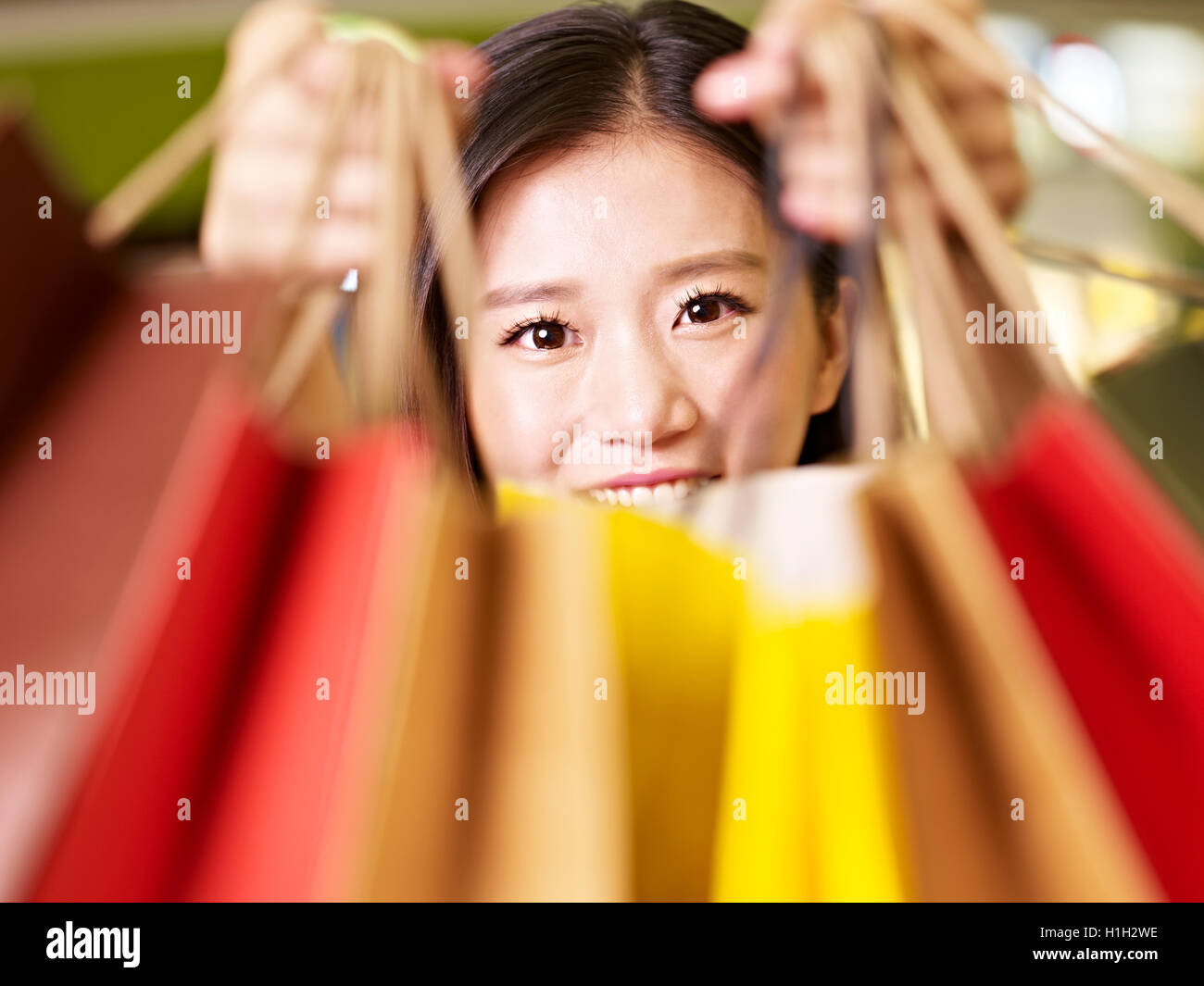 Giovane donna asiatica che mostra ciò che ella ha comprato durante un giro di shopping Foto Stock