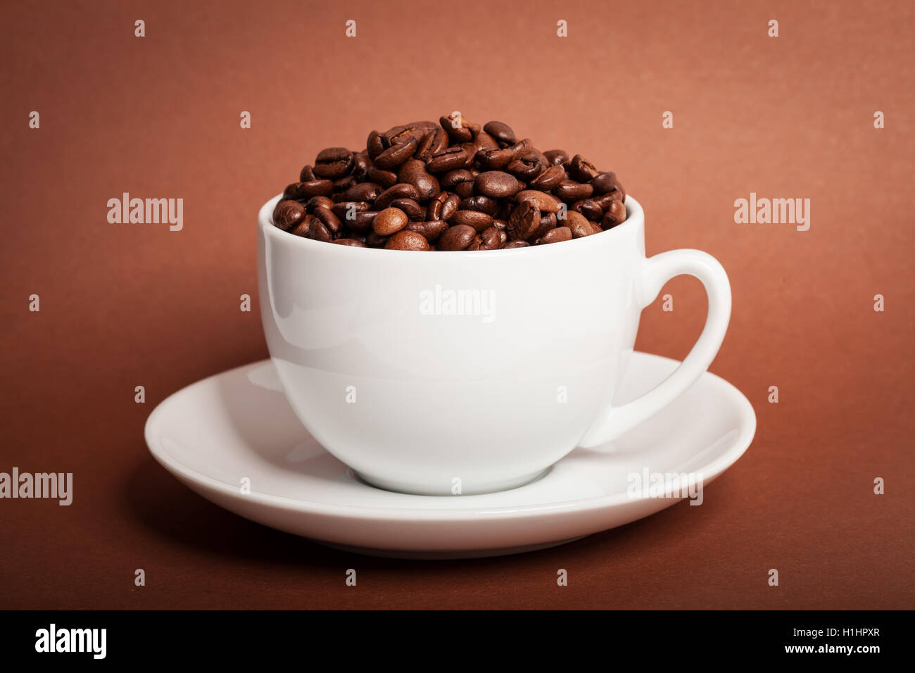 I chicchi di caffè in tazza su sfondo marrone Foto Stock
