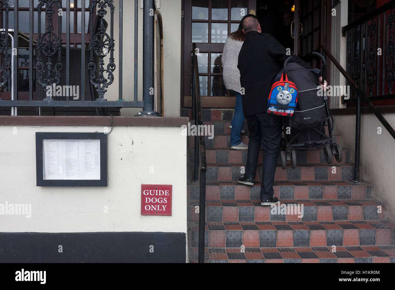 Un padre si arrampica passi di trasportare un bambino di buggy con il volto di Thomas Il serbatoio, sulla Western Esplanade a Southend. Foto Stock