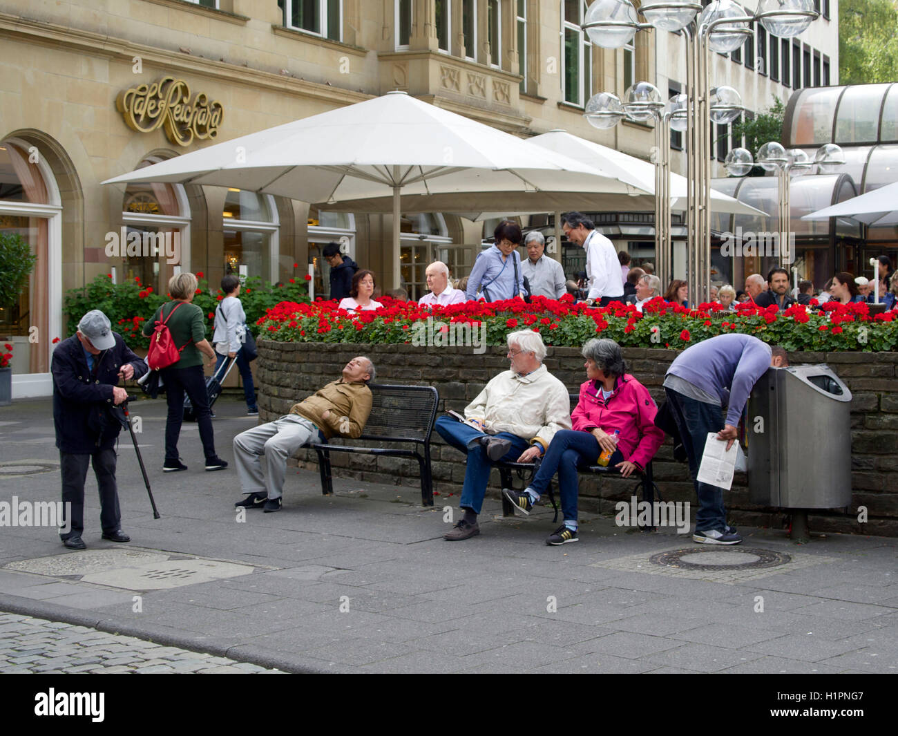 Scena di strada nel centro della città di Colonia, Germania, con l'uomo bloccato la sua testa in un cestino dell'immondizia. Foto Stock