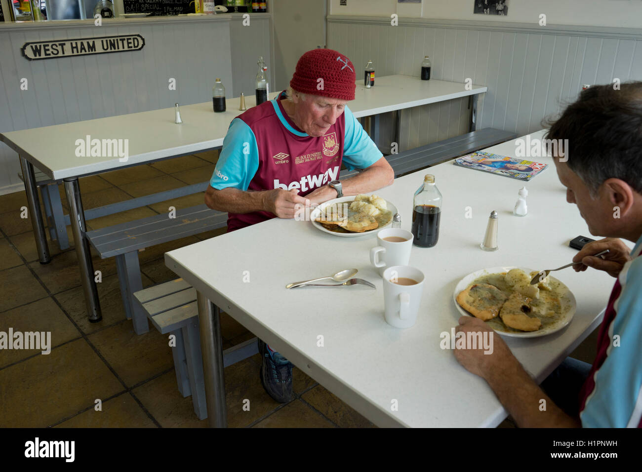 West Ham sostenitori nel kit camicie a mangiare una torta tradizionale e Mash ristorante nei pressi di Upton Park, sito del West Ham United vecchio stadio di calcio.london.UK Foto Stock