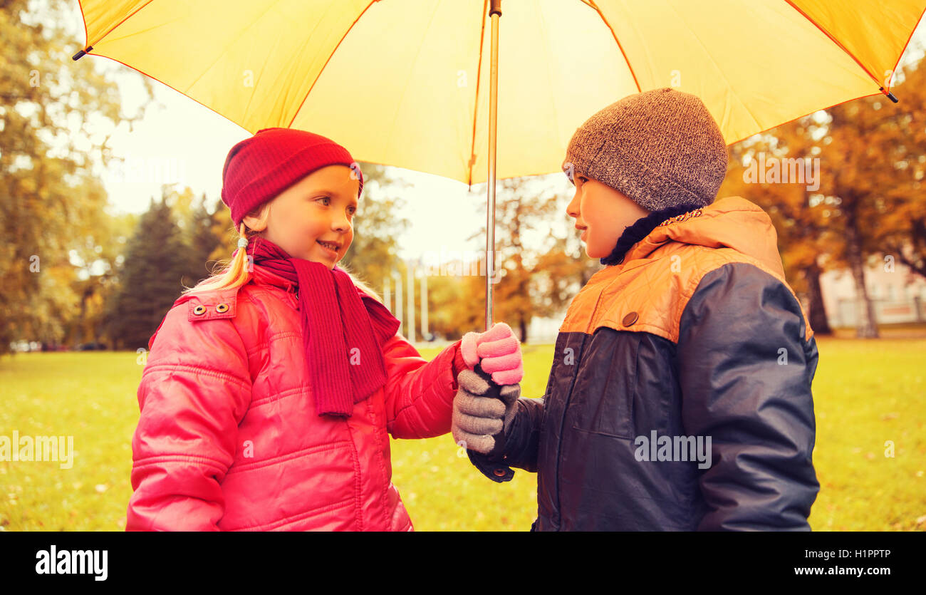 Felice un ragazzo e una ragazza con ombrello in autunno park Foto Stock