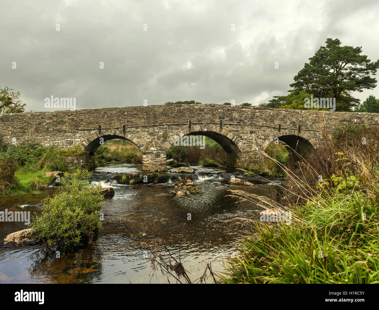 Bellissimo Dartmoor paesaggio con il ponte di pietra e a est del fiume Dart a Postbridge, Devon su un nuvoloso giorno. Foto Stock