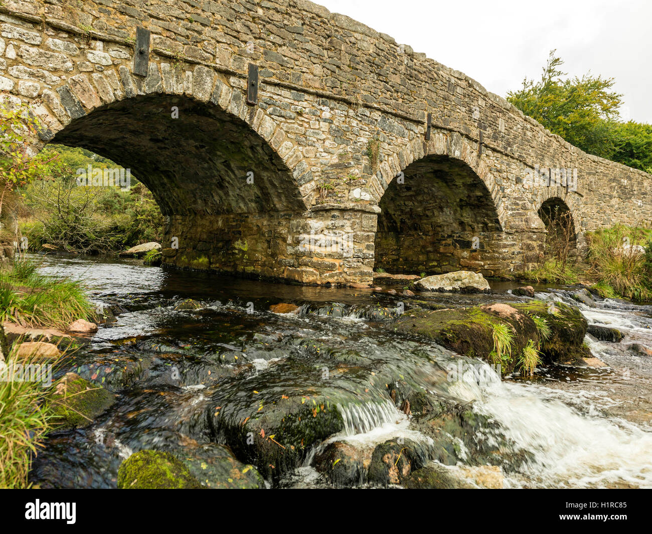 Bellissimo Dartmoor paesaggio con il ponte di pietra e a est del fiume Dart a Postbridge, Devon su un nuvoloso giorno. Foto Stock