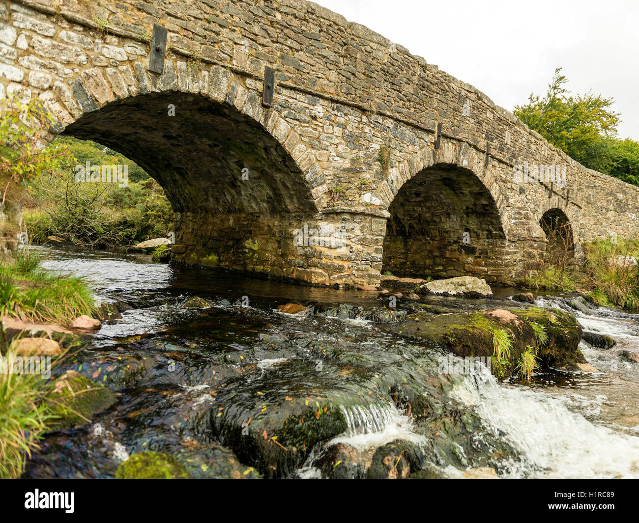 Bellissimo Dartmoor paesaggio con il ponte di pietra e a est del fiume Dart a Postbridge, Devon su un nuvoloso giorno. Foto Stock