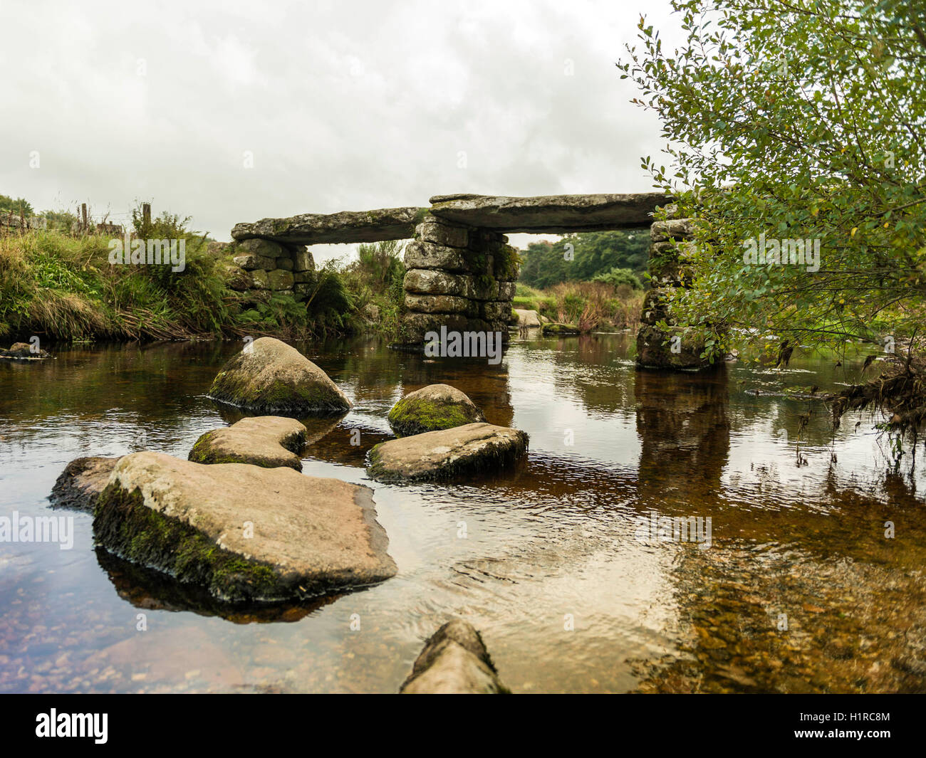 Bellissimo Dartmoor paesaggio con il ponte di pietra e a est del fiume Dart a Postbridge, Devon su un nuvoloso giorno. Foto Stock