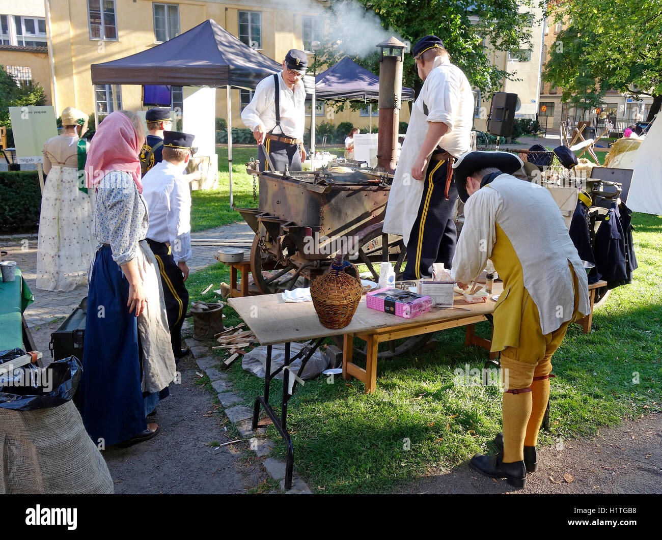 Caroleans svedese (XVII secolo) rievocazione scena. Uomini militari di preparare e servire il cibo su una stufa a legna Foto Stock