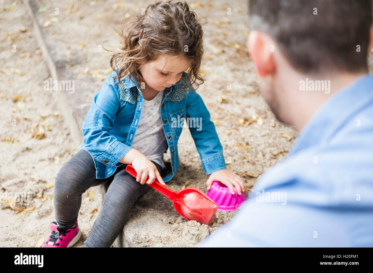 Padre giocando con la figlia in sandbox Foto Stock