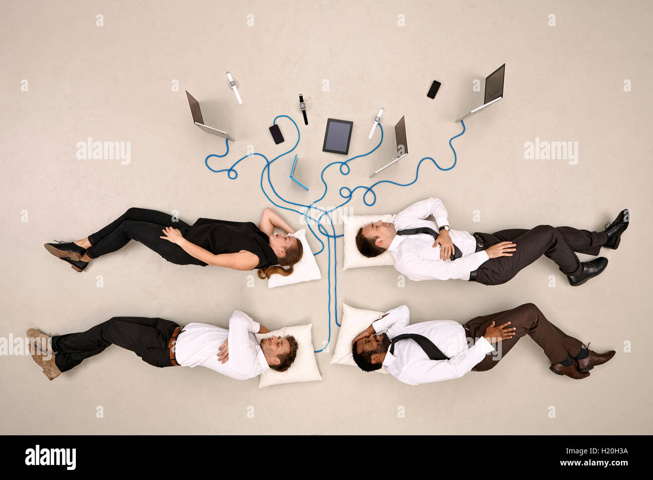 Quattro colleghi di lavoro dormendo collegato ai dispositivi mobili Foto Stock