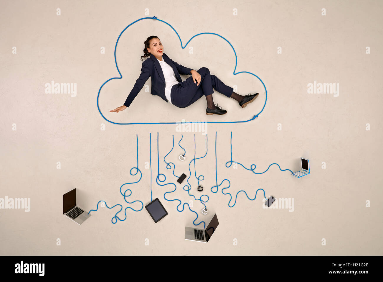Imprenditrice seduta in una nuvola collegato ai dispositivi mobili Foto Stock
