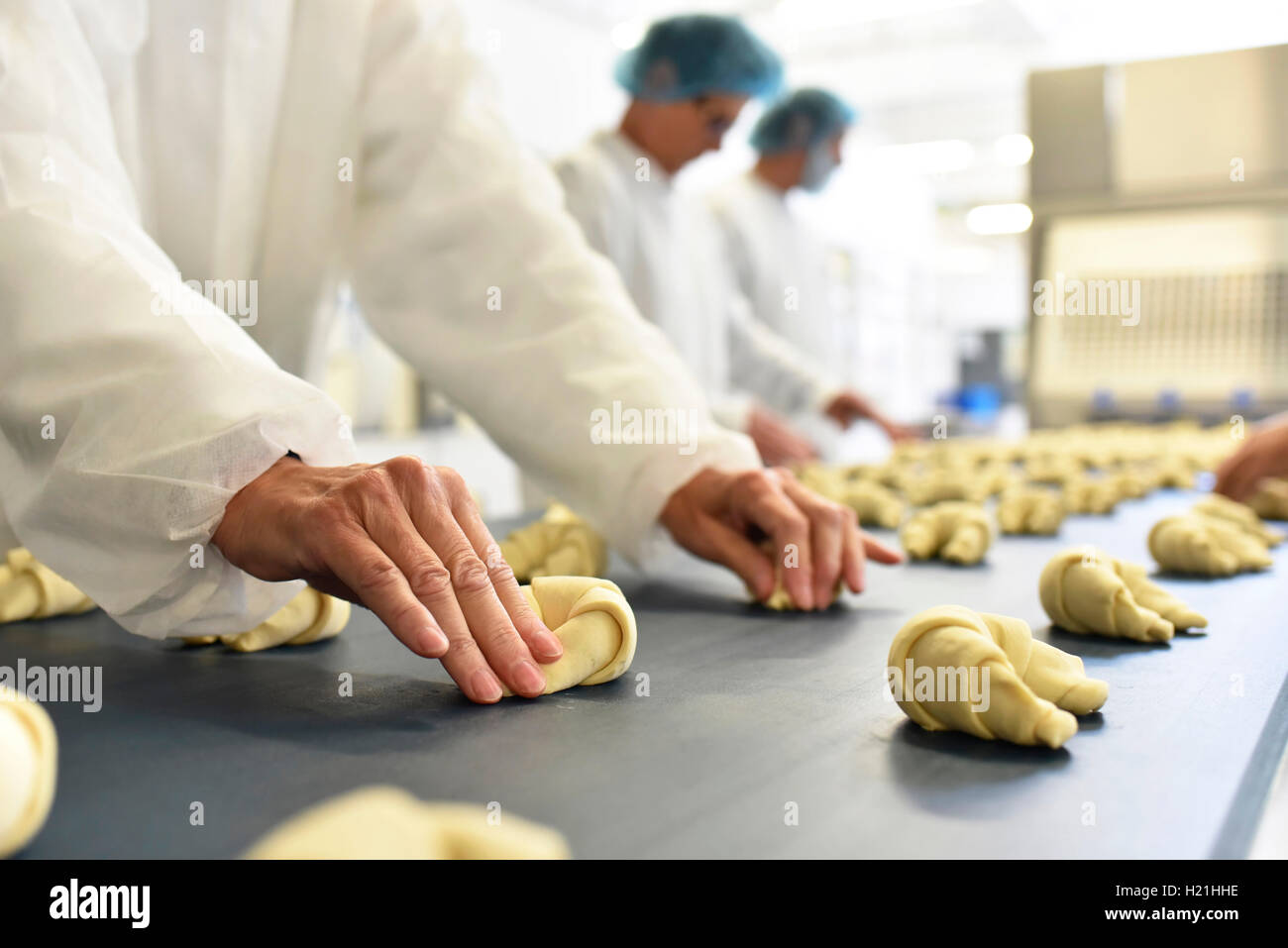 Lavoratori in linea di produzione in una fabbrica di cottura con croissant Foto Stock