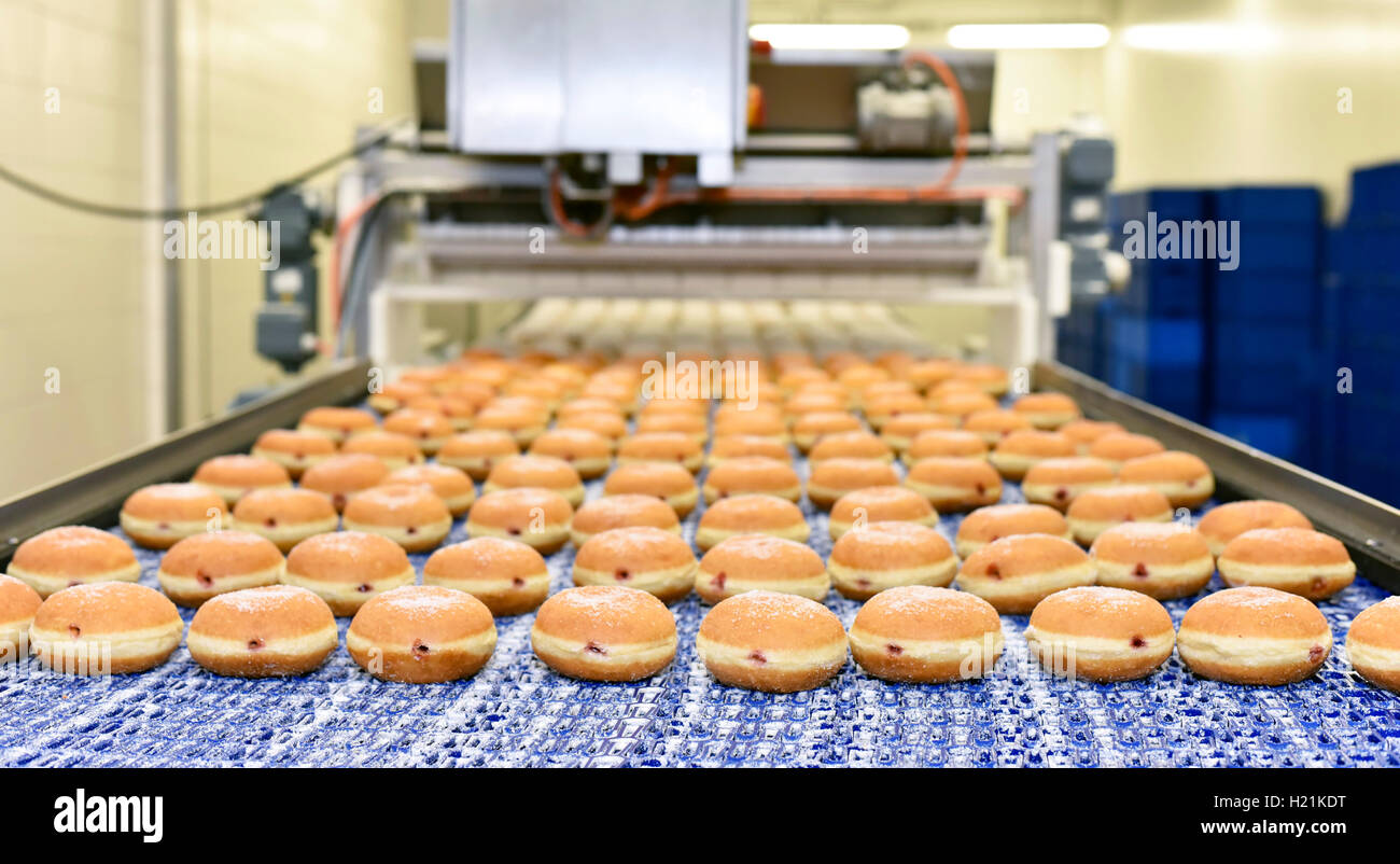 Linea di produzione in una fabbrica di cottura con i berlinesi Foto Stock