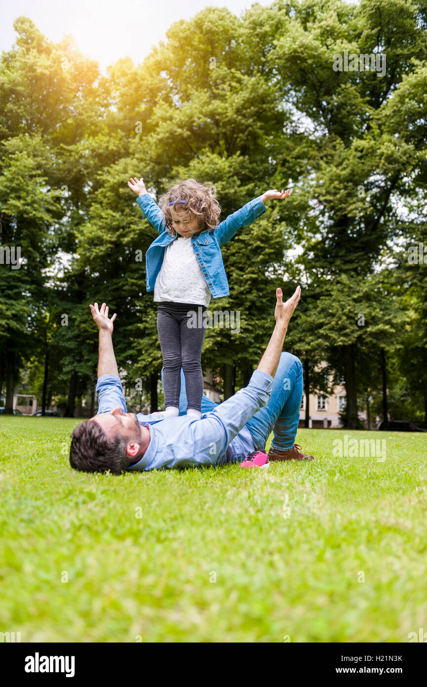 Padre e figlia giocando sul prato in posizione di parcheggio Foto Stock