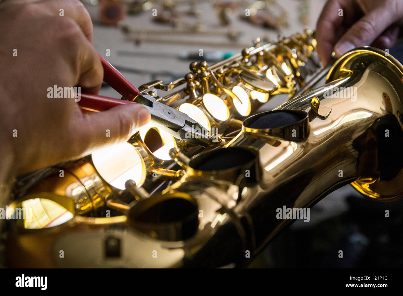 Strumento di smontaggio maker un sassofono utilizzando le pinze durante una riparazione Foto Stock