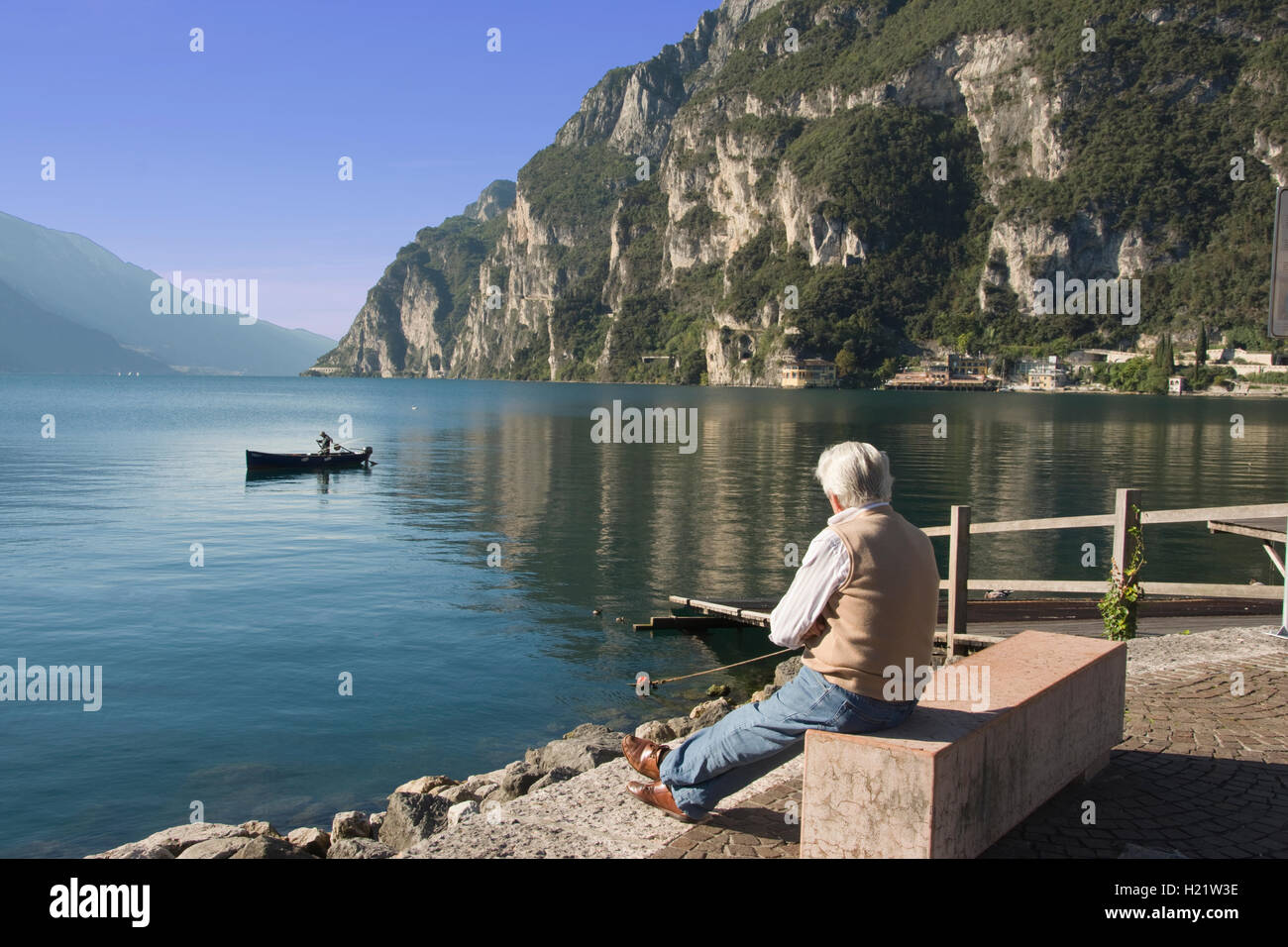 L'Europa, in Italia, in provincia di Trento, il Lago di Garda, Riva del Garda, l'uomo la visualizzazione di barche da pesca sul lago Foto Stock