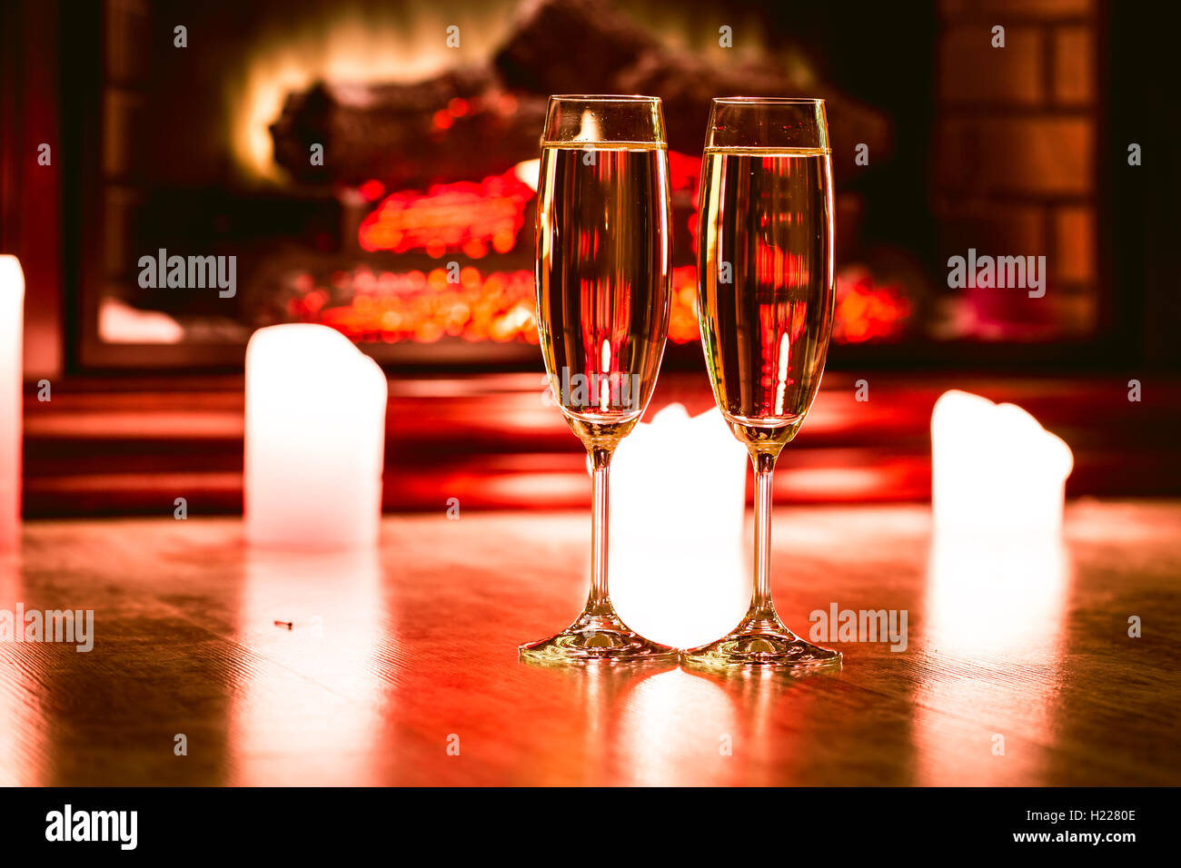 Due bicchiere di champagne con candele davanti al camino nell'interno di natale Foto Stock