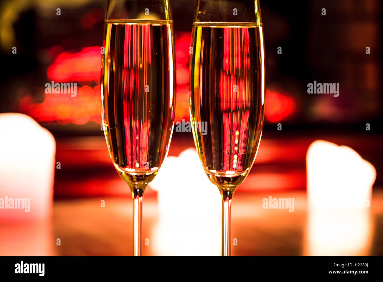 Due bicchiere di champagne con candele davanti al camino nell'interno di natale Foto Stock