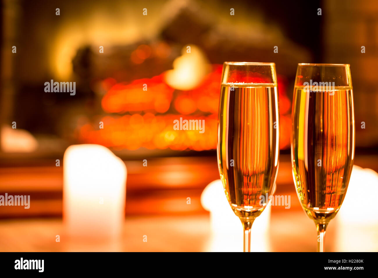 Due bicchiere di champagne con candele davanti al camino nell'interno di natale Foto Stock