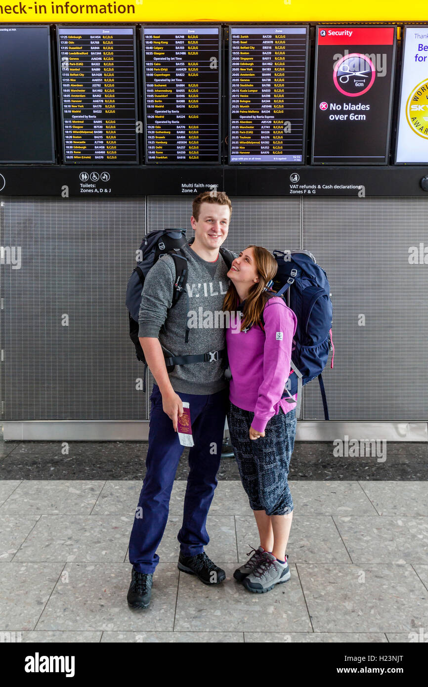 Un Backpacking giovane pongono di fronte alla scheda di partenza all'aeroporto di Heathrow Terminal 5 di Londra, Regno Unito Foto Stock