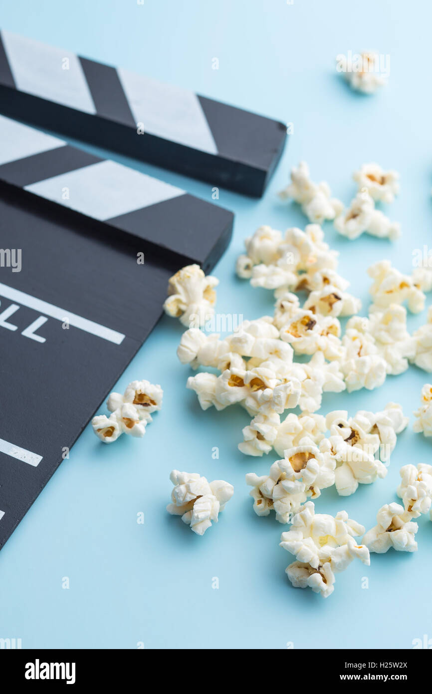 Popcorn e clapperboard su sfondo colorato. Foto Stock