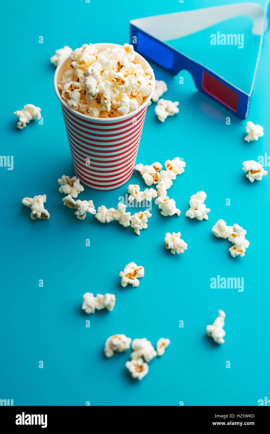 Popcorn e occhiali 3D su sfondo blu. Foto Stock
