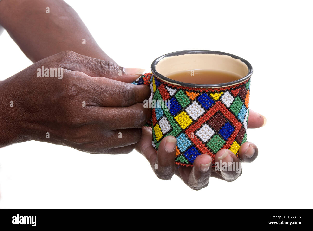 African la mano che regge una tazza di stagno decorate con perle in un Xhosa design. Foto Stock