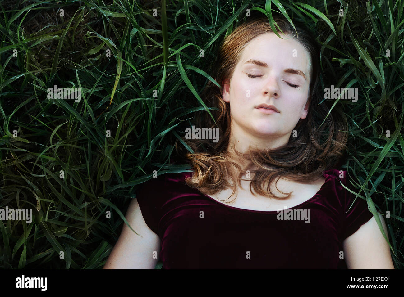 Ragazza posa in erba verde al di fuori Foto Stock