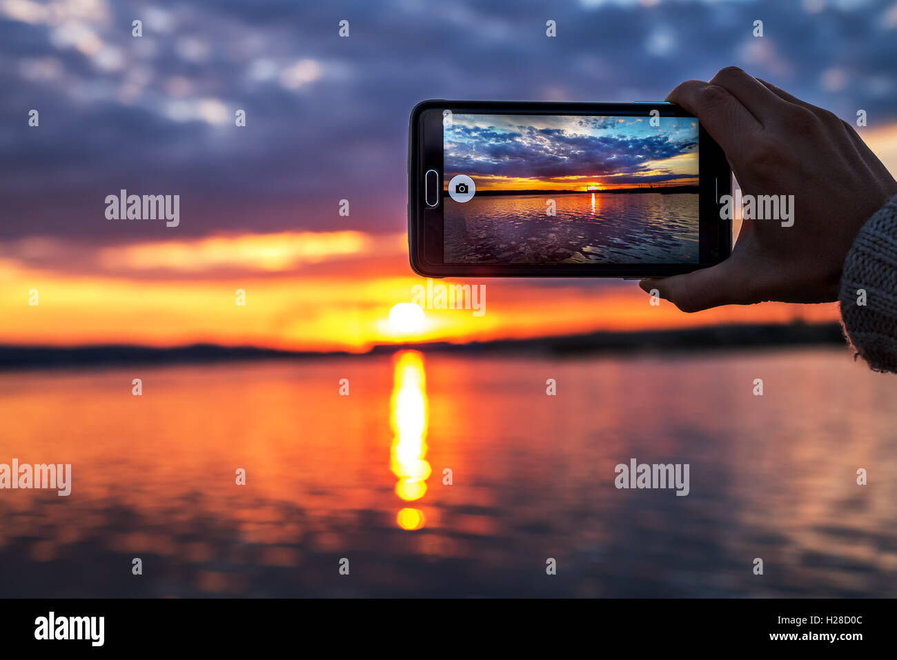 Donna mani tenendo il telefono cellulare al tramonto. Foto Stock