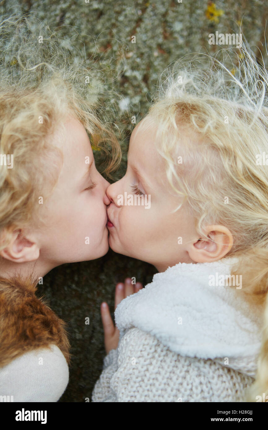 Bacio tra due piccole sorelle come segno dei Gemelli di amore e di affetto per bambini Foto Stock