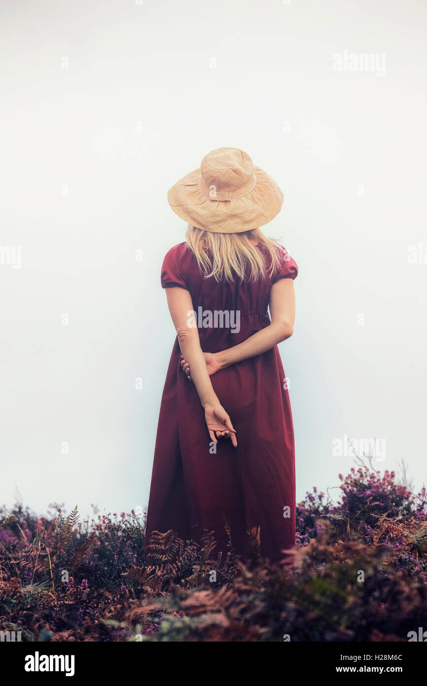 Una ragazza in un abito rosso è in piedi nel heather Foto Stock